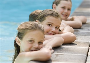 Girls in a row leaning on edge of swimming pool. Date : 2008