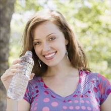 Woman drinking bottled water outdoors. Date : 2008