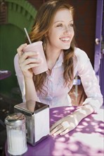 Woman drinking smoothie in outdoor cafe. Date : 2008