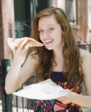 Young woman eating pizza in urban setting. Date : 2008