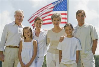 Multi-generational family posing in front of American flag.