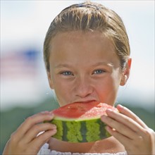 Girl eating watermelon outdoors.