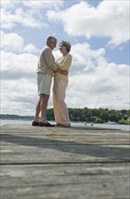 Senior couple hugging on dock.