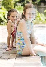 Girls sitting on edge of swimming pool. Date : 2008