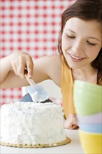 Teenage girl frosting cake. Date : 2008