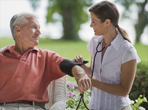 Nurse checking senior man’s blood pressure.