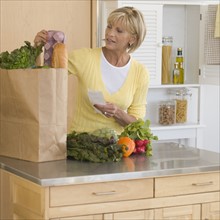 Woman unpacking groceries in kitchen.