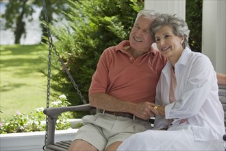 Senior couple sitting on porch swing.