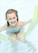 Girl playing on inflatable raft in swimming pool. Date : 2008