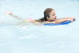Girl using kickboard in swimming pool. Date : 2008