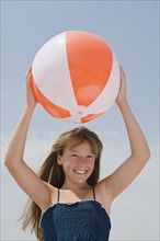 Girl holding beach ball above head.