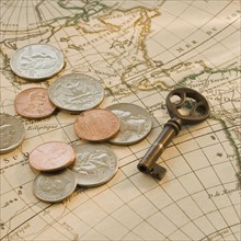 Close up of coins and key on map.