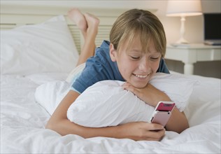 Girl using cell phone on bed.