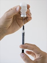 Close up of man filling syringe.