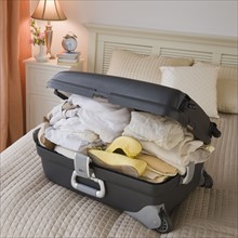 Full suitcase on bed.