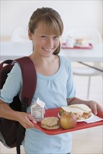 Girl carrying lunch tray in school cafeteria.