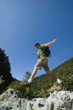 Hiker jumping across rocks. Date : 2008
