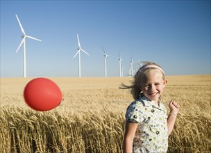 Girl holding balloon on wind farm. Date : 2008