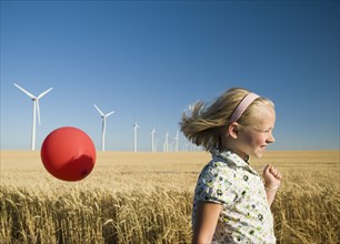 Girl holding balloon on wind farm. Date : 2008