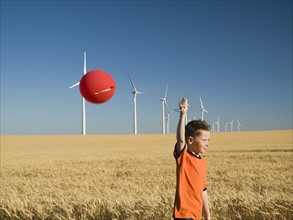 Boy holding balloon on wind farm. Date : 2008