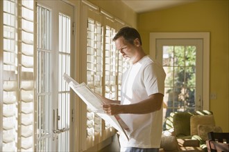 Man reading newspaper in livingroom. Date : 2008