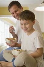 Father and son eating breakfast on kitchen counter. Date : 2008