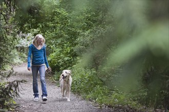 Girl walking dog on forest path. Date : 2008