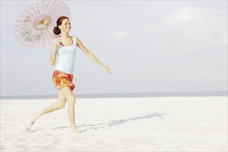 Girl running on beach with umbrella. Date : 2008