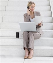 Businesswoman working on laptop and talking on cell phone. Date : 2008