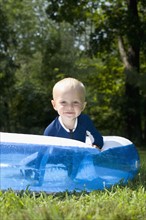 Baby boy playing in inflatable swimming pool. Date : 2008