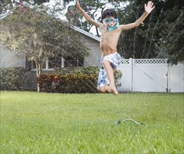 Boy jumping through sprinkler. Date : 2008