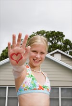Girl holding out hand painted with heart design. Date : 2008