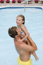 Father lifting daughter out of swimming pool. Date : 2008