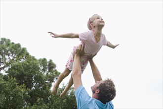 Father lifting daughter in backyard. Date : 2008