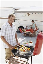 Man grilling dinner for family on beach. Date : 2008