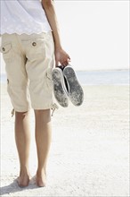 Young woman walking barefoot on beach. Date : 2008