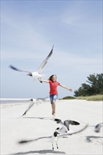 Girl chasing birds on beach. Date : 2008