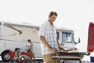 Man grilling dinner for family on beach. Date : 2008