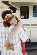 Father carrying sleepy daughter and starfish to motor home. Date : 2008