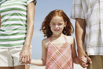 Girl holding hands with mother and father. Date : 2008