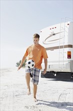 Young man playing with soccer ball on beach. Date : 2008