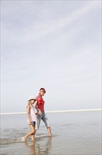 Mother and daughter walking in ocean. Date : 2008