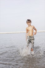 Boy splashing in ocean. Date : 2008