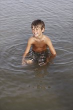 Boy sitting in shallow water. Date : 2008
