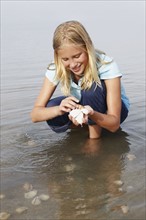 Girl looking for shells in shallow water. Date : 2008