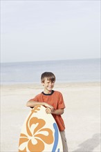 Boy holding skimboard on beach. Date : 2008