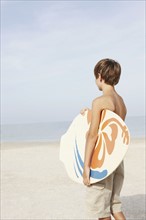 Boy holding skimboard on beach. Date : 2008