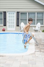Boy stepping out of swimming pool. Date : 2008