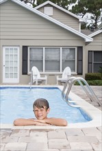 Boy leaning on edge of swimming pool. Date : 2008