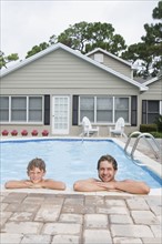 Father and son leaning on edge of swimming pool. Date : 2008
